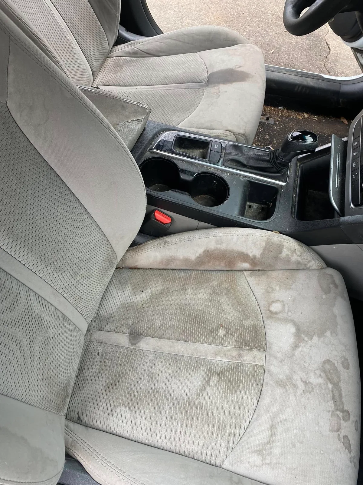 Stained front cloth seats and dirty center console before detailing